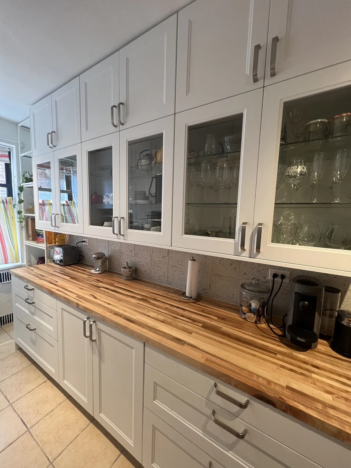 White IKEA glass-front display cabinets over butcher block countertop