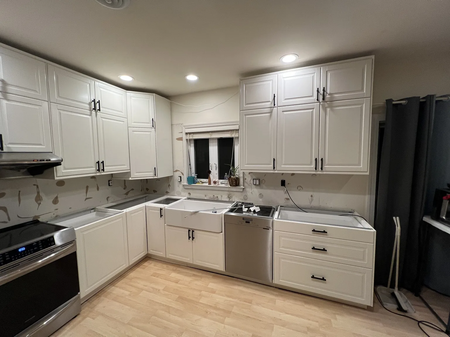 Completed white IKEA kitchen with shaker cabinets, farmhouse sink, and stainless appliances